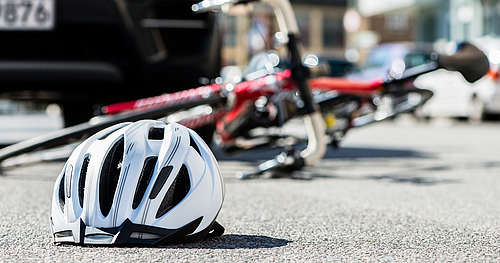 Fahrradhelm und umgestürztes Fahrrad auf der Straße nach Unfall