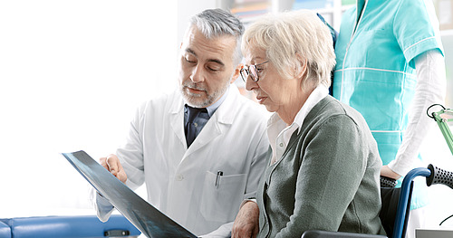Arzt erklärt älterer Patientin Röntgenbild