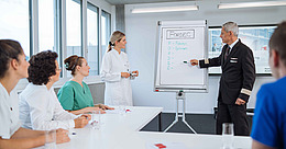 Pilot zeigt auf Whiteboard, Ärztin schaut zu, während eines HFCT-Kurses