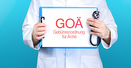 Arzt hält blaues Schild mit der Aufschrift "GOÄ (Gebührenordnung für Ärzte)"
