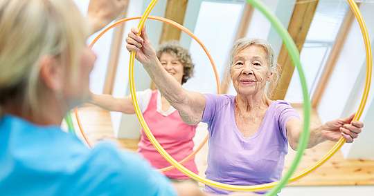 Senioren machen Firnessübungen mit Hula-Hoop-Reifen