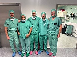 Fellows und Ärzte in OP-Kleidung vor OP-Saal
